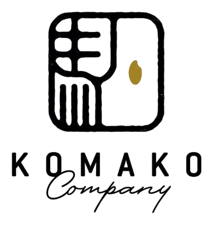KOMAKO Company(株式会社駒子)のロゴ。手彫りの落款の中に「駒」を崩した線画があり、右上に金の米粒がひとつ置かれている